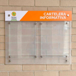 Cartelera informativa de acrílico transparente con bolsillos para hojas intercambiables instalada sobre pared de ladrillo.
