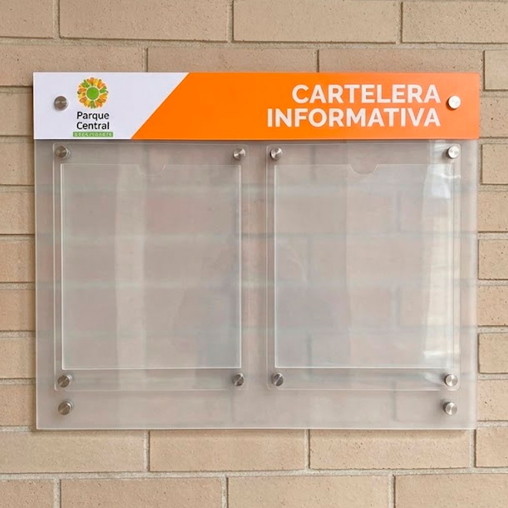 Cartelera informativa de acrílico transparente con bolsillos para hojas intercambiables instalada sobre pared de ladrillo.